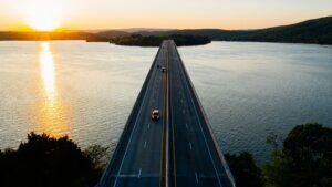 Image of cars driving on bridge over water into sunset